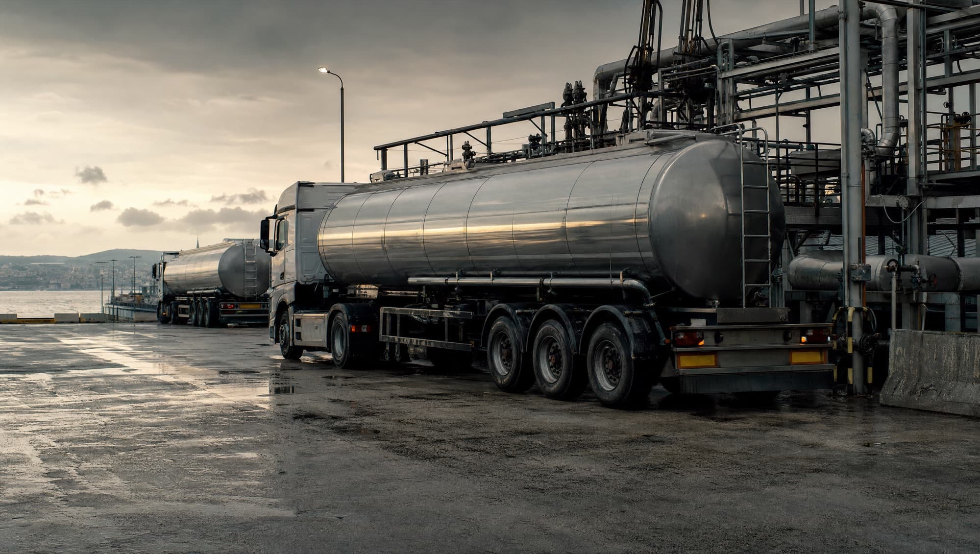 Stainless fuel tanker trucks staged at a terminal for road delivery