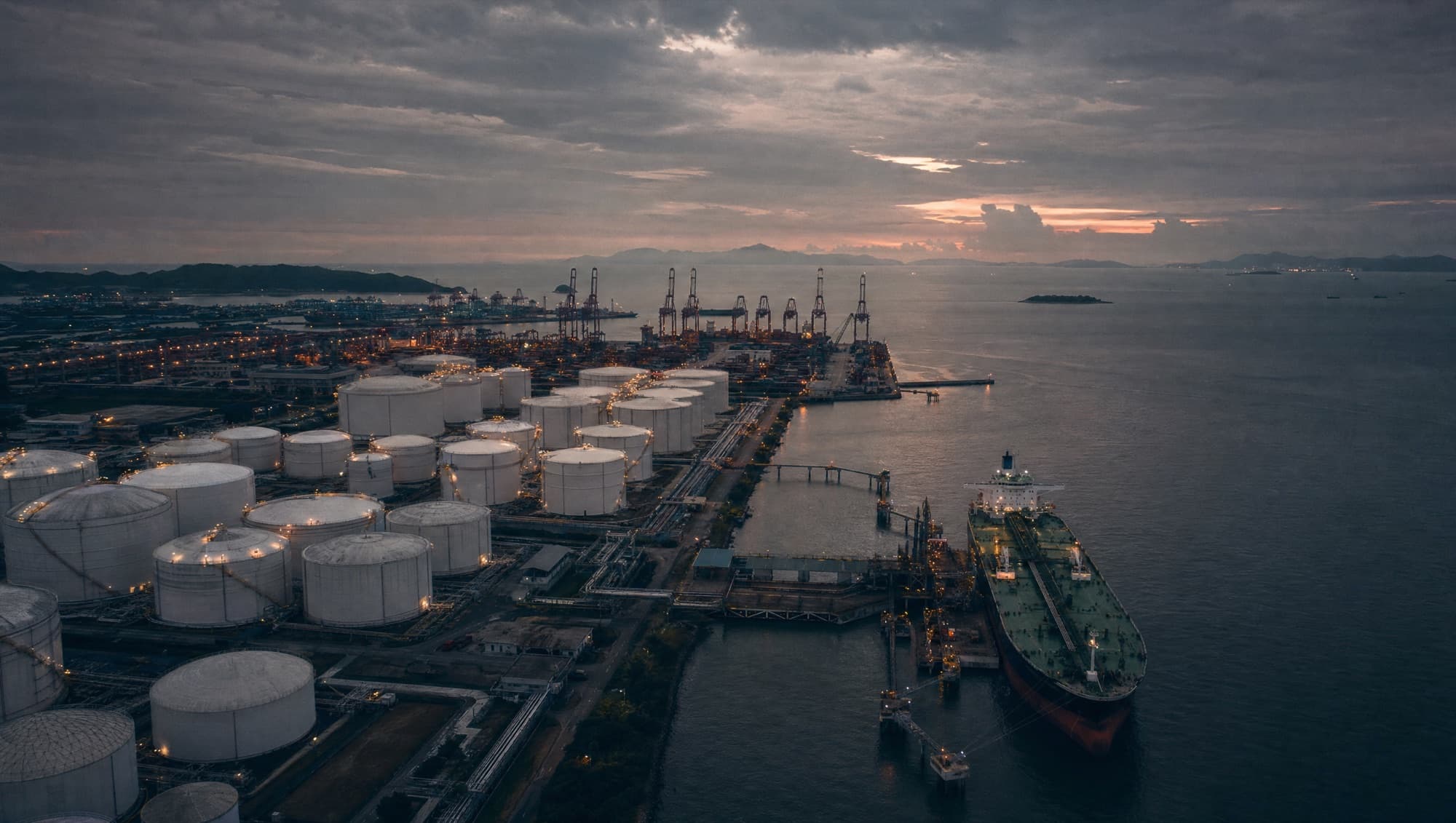 Aerial view of a fuel tank farm beside a berthed tanker at dusk