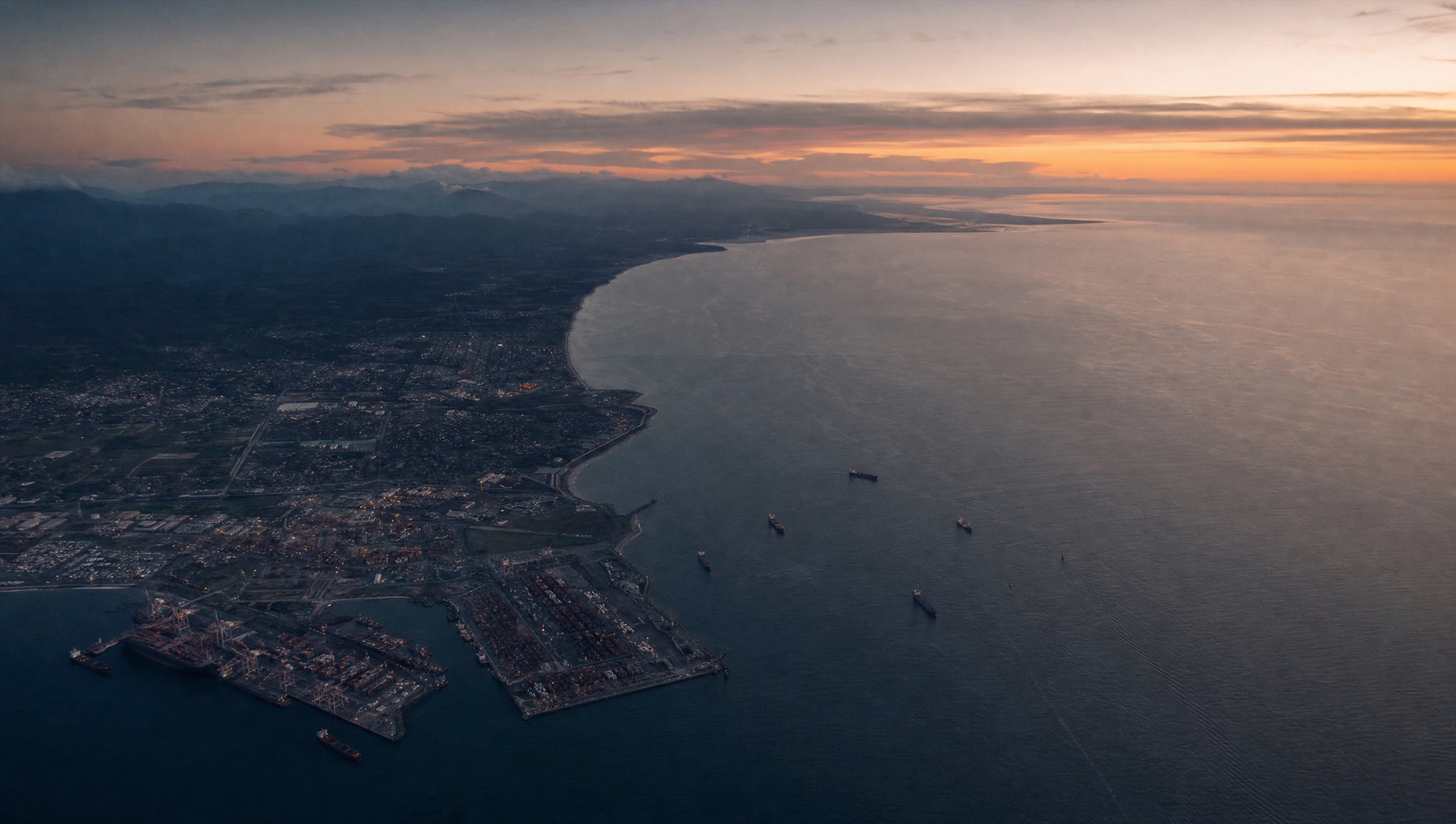 Aerial view of a working coastline and port with vessels at anchor